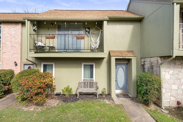 9009 N Plz Unit 118, Austin, TX 78753 - property entrance with a balcony, stucco siding, roof with shingles, and stone siding