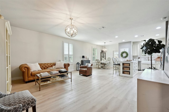 living room with an inviting chandelier and light wood-type flooring