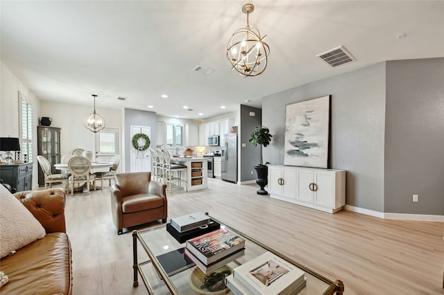 living room featuring light wood-type flooring and a notable chandelier