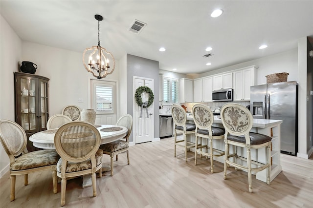 dining room with an inviting chandelier and light hardwood / wood-style flooring