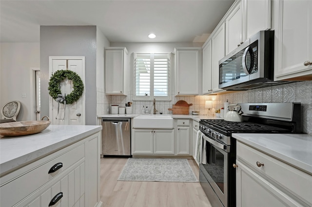 kitchen with tasteful backsplash, appliances with stainless steel finishes, sink, and white cabinets