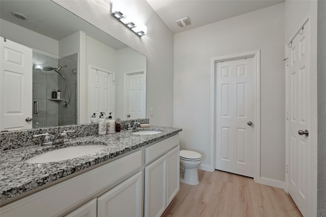 bathroom featuring an enclosed shower, vanity, wood-type flooring, and toilet