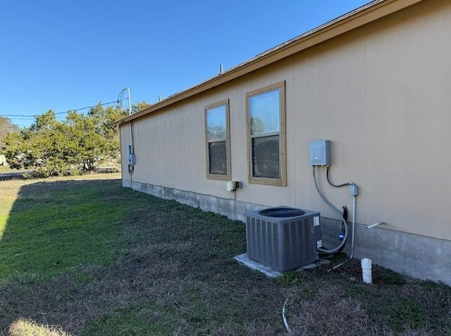 view of side of home featuring central AC and a yard