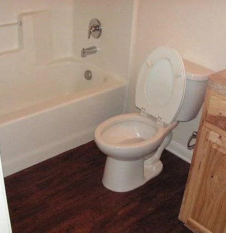 full bathroom with shower / washtub combination, hardwood / wood-style flooring, toilet, and vanity