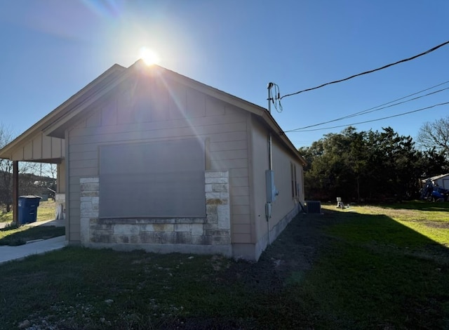 view of side of home featuring central air condition unit and a yard