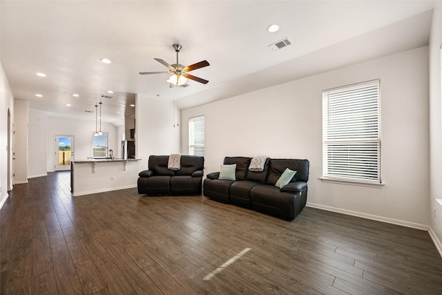 living room featuring a healthy amount of sunlight, dark wood-type flooring, and ceiling fan