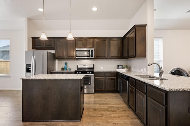 kitchen featuring hanging light fixtures, a center island, appliances with stainless steel finishes, and sink