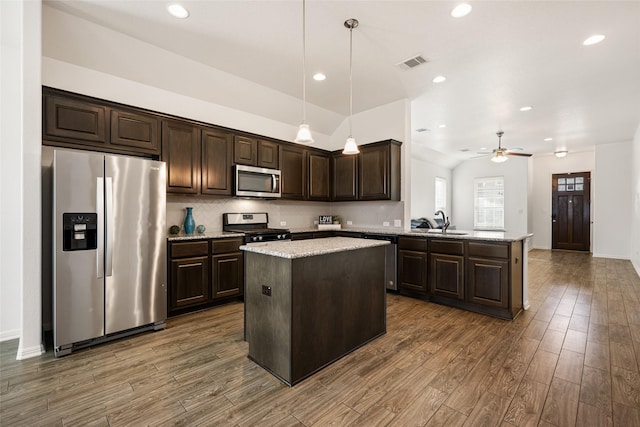 kitchen with dark brown cabinetry, a center island, appliances with stainless steel finishes, kitchen peninsula, and pendant lighting