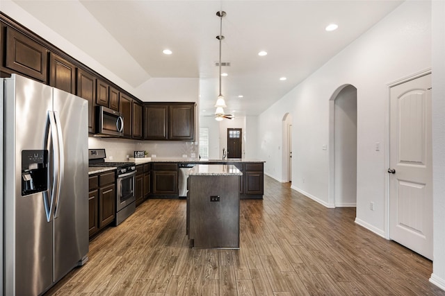 kitchen with pendant lighting, dark brown cabinets, stainless steel appliances, and a kitchen island