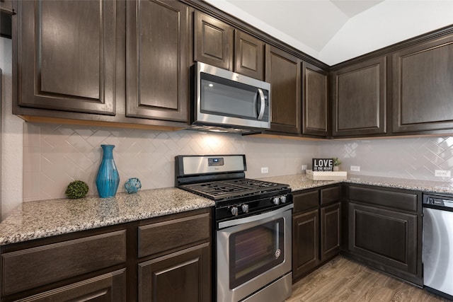 kitchen with lofted ceiling, light hardwood / wood-style flooring, dark brown cabinets, stainless steel appliances, and light stone counters