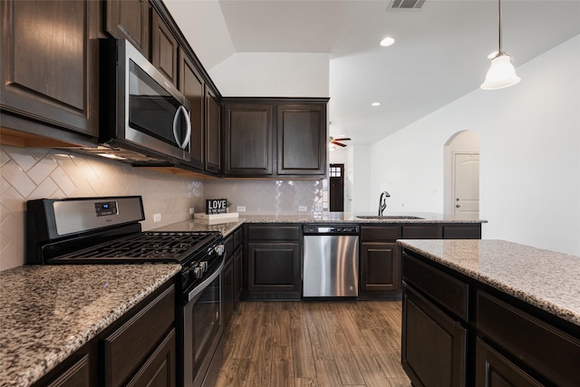 kitchen featuring appliances with stainless steel finishes, sink, hanging light fixtures, light stone countertops, and dark wood-type flooring