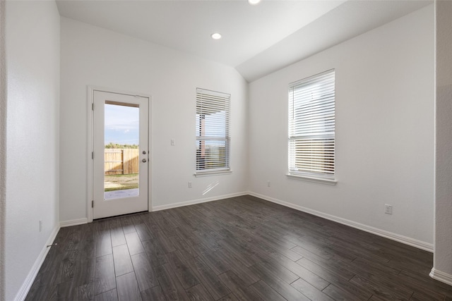 unfurnished room featuring vaulted ceiling, plenty of natural light, and dark wood-type flooring