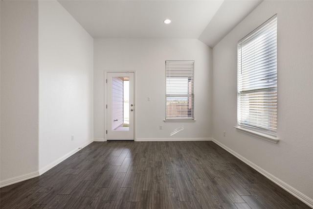 spare room featuring lofted ceiling and dark hardwood / wood-style flooring