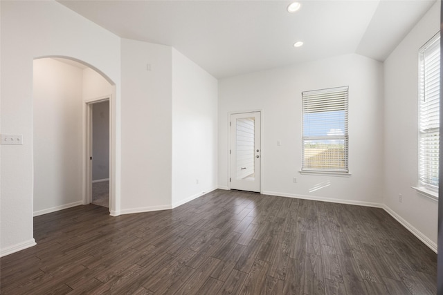 spare room featuring dark wood-type flooring and vaulted ceiling