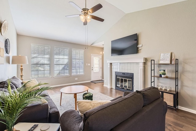 living room featuring vaulted ceiling, dark hardwood / wood-style floors, ceiling fan, and a fireplace