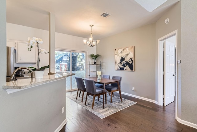 dining space with an inviting chandelier, sink, and dark hardwood / wood-style floors