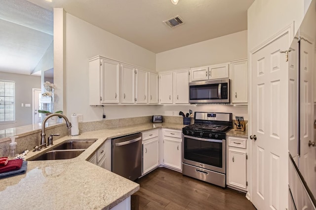 kitchen with appliances with stainless steel finishes, sink, white cabinets, and kitchen peninsula