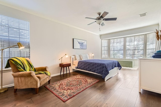 bedroom featuring dark wood-type flooring, ceiling fan, crown molding, and radiator