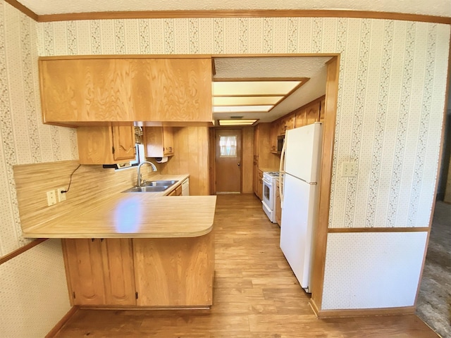 kitchen featuring kitchen peninsula, white appliances, light hardwood / wood-style flooring, and sink