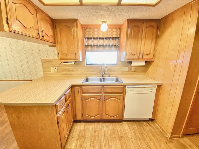 kitchen with a textured ceiling, dishwasher, sink, light hardwood / wood-style flooring, and kitchen peninsula