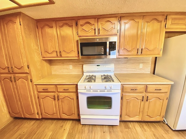 kitchen with light hardwood / wood-style floors, white gas stove, and refrigerator