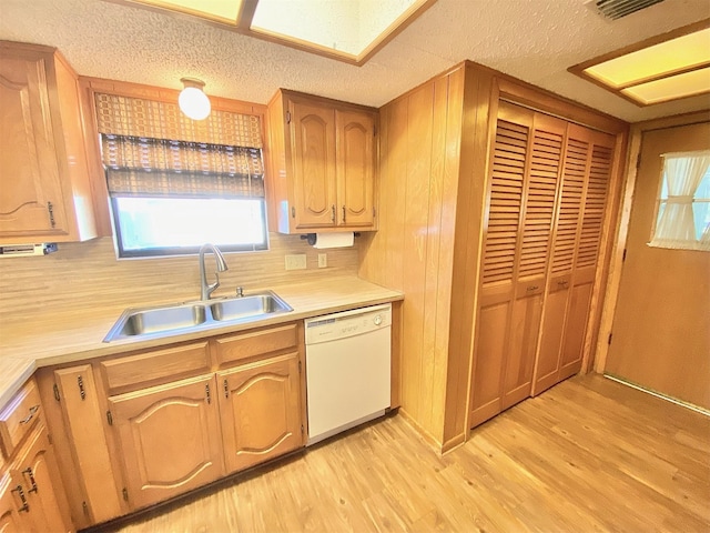 kitchen with sink, light hardwood / wood-style flooring, a textured ceiling, and dishwasher