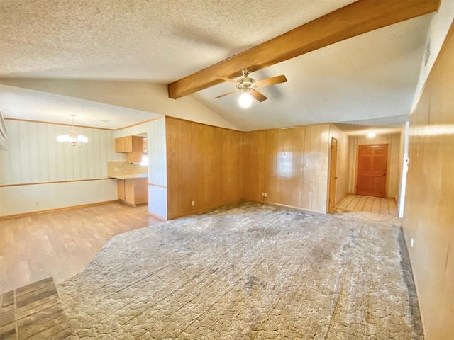 interior space featuring ceiling fan with notable chandelier, a textured ceiling, wooden walls, and vaulted ceiling with beams