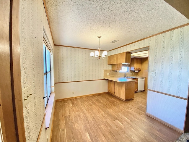 kitchen with light hardwood / wood-style floors, dishwasher, a chandelier, hanging light fixtures, and kitchen peninsula