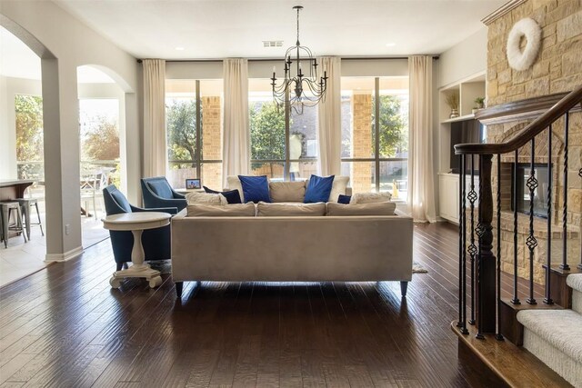 living room with dark hardwood / wood-style floors, a wealth of natural light, built in features, and an inviting chandelier