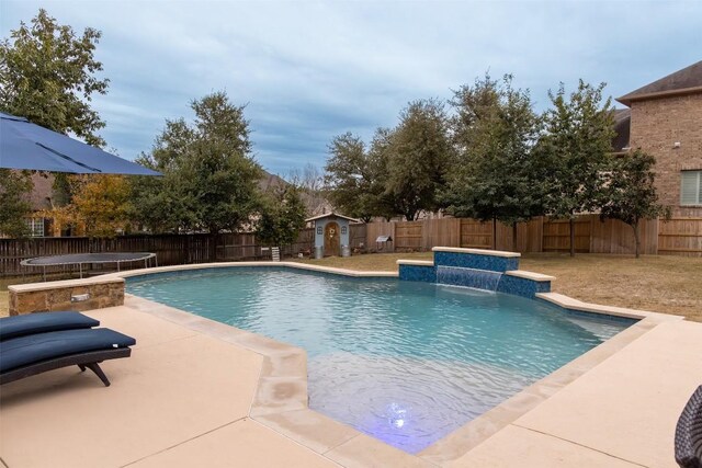 view of swimming pool featuring pool water feature, a trampoline, and a storage unit