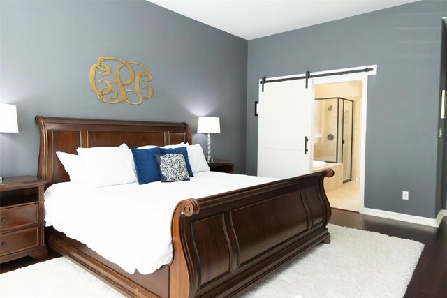 bedroom featuring connected bathroom, hardwood / wood-style flooring, and a barn door