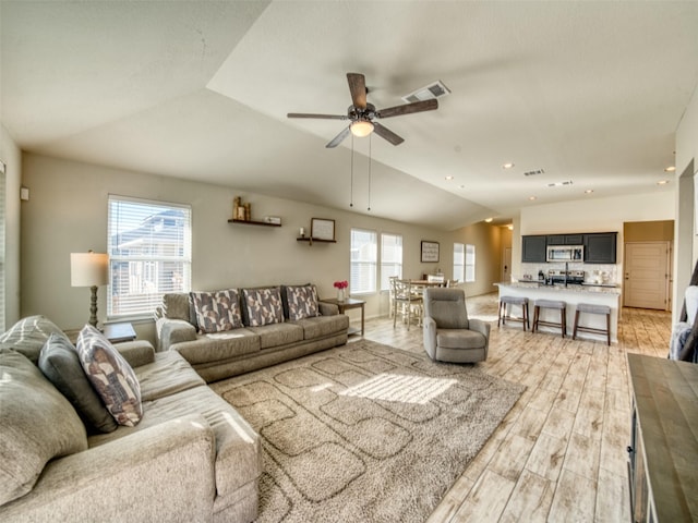 living room with light wood-type flooring, vaulted ceiling, and ceiling fan