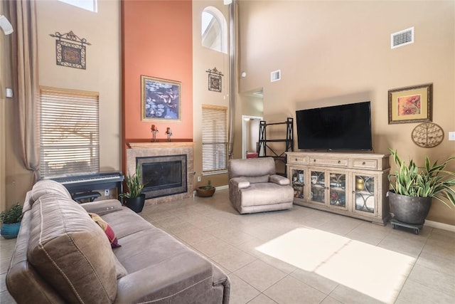 1201 Drake Cv, Leander, TX 78641 - tiled living area featuring a towering ceiling, healthy amount of natural light, baseboards, and a tiled fireplace