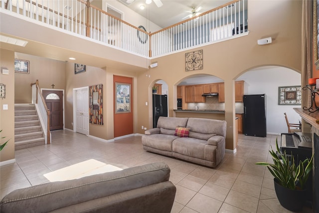 tiled living room with ceiling fan and a high ceiling