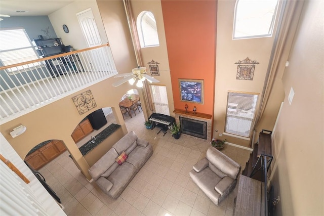 1201 Drake Cv, Leander, TX 78641 - living area featuring a towering ceiling, light tile patterned floors, a ceiling fan, healthy amount of natural light, and a tile fireplace