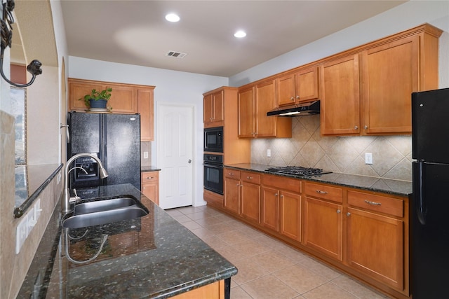 kitchen featuring sink, backsplash, light tile patterned floors, dark stone countertops, and black appliances