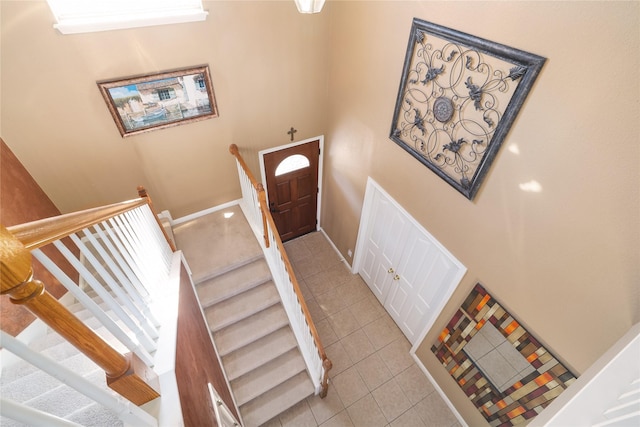 stairway with a high ceiling and tile patterned floors