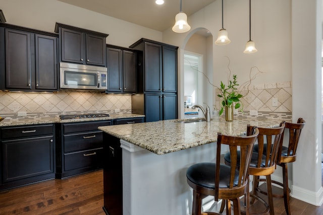 kitchen with tasteful backsplash, decorative light fixtures, a breakfast bar, stainless steel appliances, and dark hardwood / wood-style floors