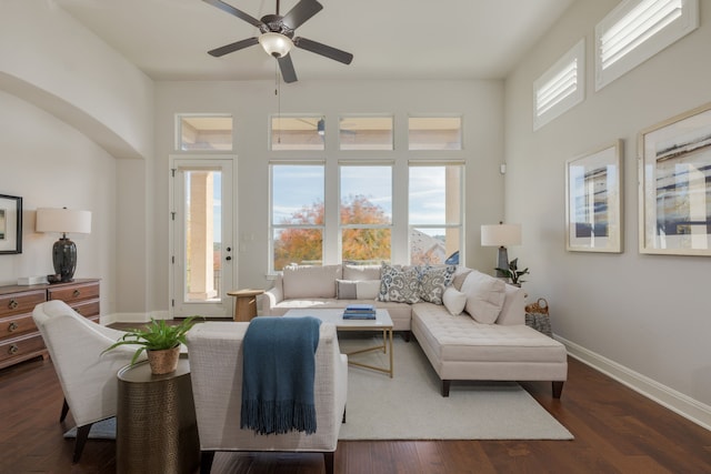 living room featuring ceiling fan, dark wood-type flooring, and a healthy amount of sunlight