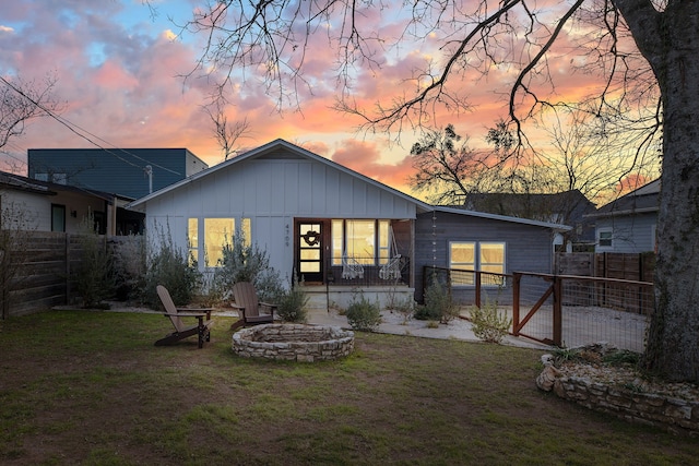 back house at dusk featuring an outdoor fire pit and a yard