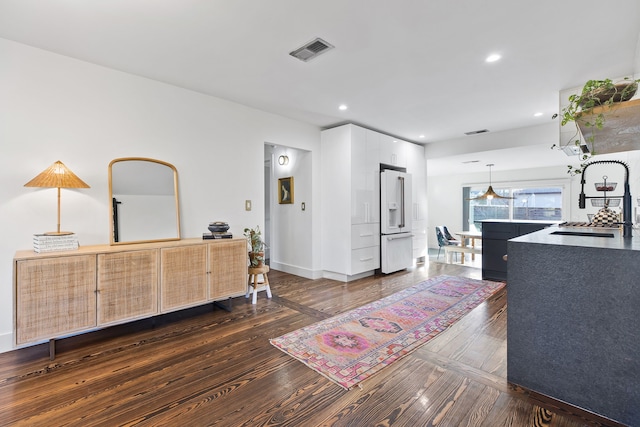 interior space featuring pendant lighting, high end white fridge, sink, white cabinets, and dark hardwood / wood-style floors