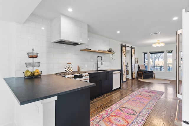 kitchen with kitchen peninsula, sink, a barn door, stove, and a breakfast bar