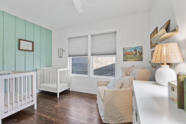 bedroom featuring dark wood-type flooring and a crib