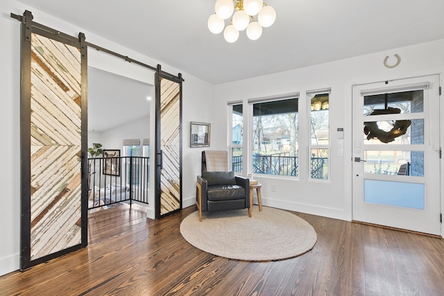 living area with dark wood-type flooring, a notable chandelier, a barn door, and vaulted ceiling