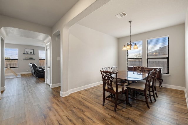 dining space with hardwood / wood-style flooring and a notable chandelier