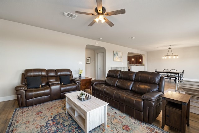 living room featuring ceiling fan with notable chandelier and light hardwood / wood-style flooring