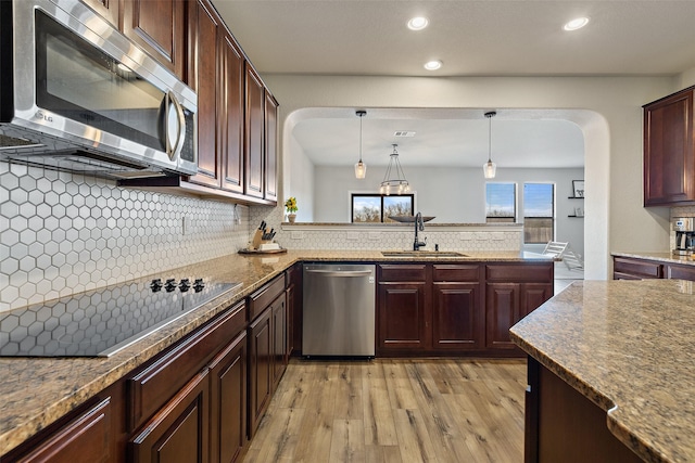 kitchen with hanging light fixtures, decorative backsplash, sink, light hardwood / wood-style flooring, and stainless steel appliances