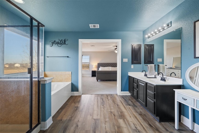 bathroom with hardwood / wood-style floors, a textured ceiling, vanity, ceiling fan, and separate shower and tub