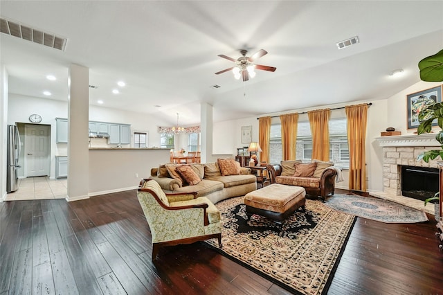 living area featuring lofted ceiling, wood-type flooring, visible vents, and a fireplace