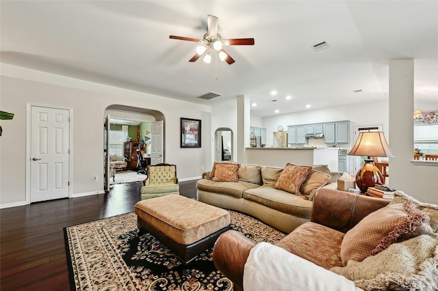 living area with dark wood-style floors, arched walkways, recessed lighting, visible vents, and baseboards